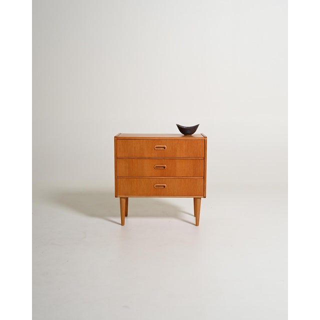 Teak bedside table with three drawers. Scandinavian production, 1950s/1960s. Made in Scandinavia between the 1950s and...