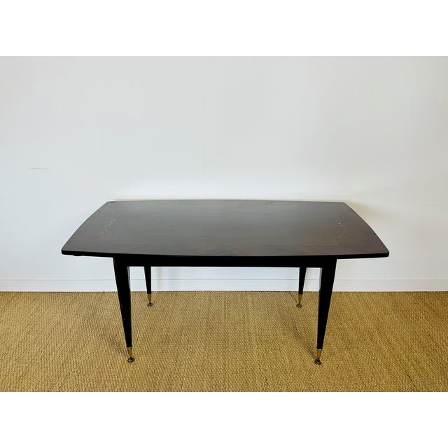 An elegant rectangular dining table dating from the 1940s-1950s, featuring a stunning Macassar veneer top with a rich,...