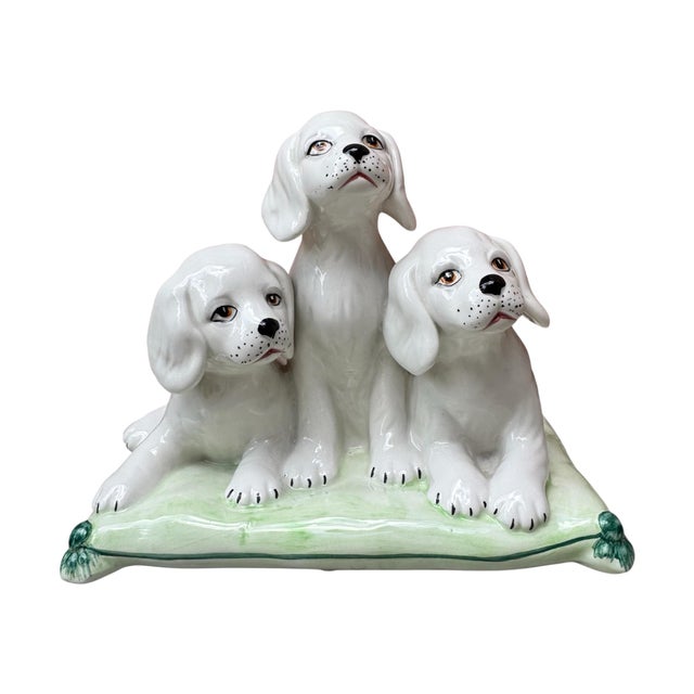 This beautifully crafted one piece porcelain sculpture features three white puppies huddled together on a light green...