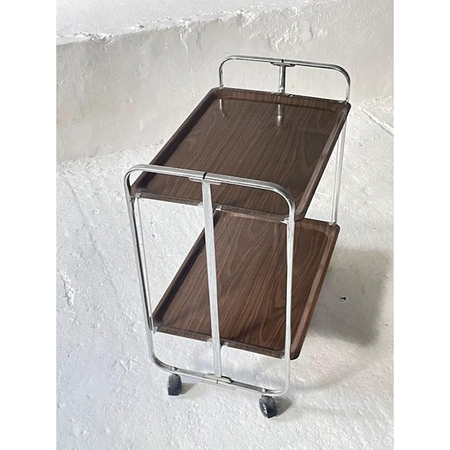 Mid-Century Modern vintage serving trolley from Germany, dating back to the 1950s. This space-saving, two-tier tea cart is...