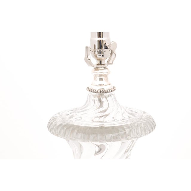 A finely cut crystal table lamp with faceted detailing, silvered feet, and a classical urn silhouette. The highly...