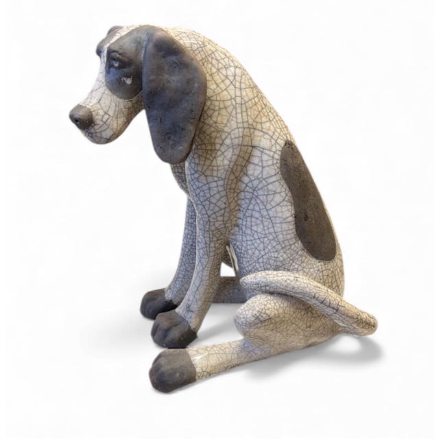 This delightful ceramic dog sculpture captures a hound-like breed in a relaxed, seated pose with a gentle, expressive...