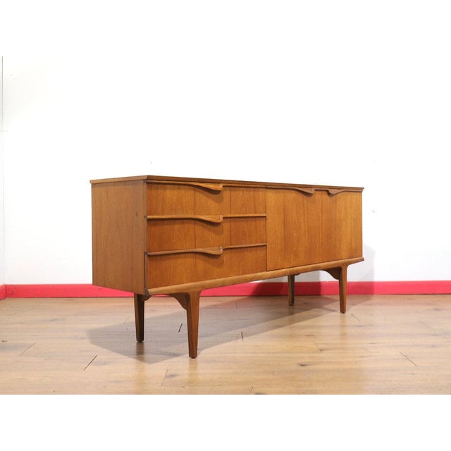 A stunning Mid eCentury Credenza, this vintage teak British sideboard perfectly embodies the timeless elegance sought by...