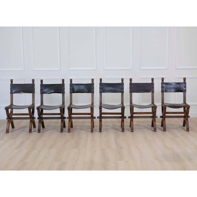 A handsome set of six mid-20th century Spanish dining chairs crafted from richly toned walnut and upholstered in warm...