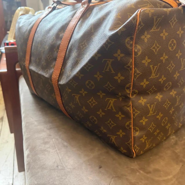 This vintage Louis Vuitton Sac Souple 55 duffle bag features the classic LV monogram-coated canvas paired with rich, dark-...