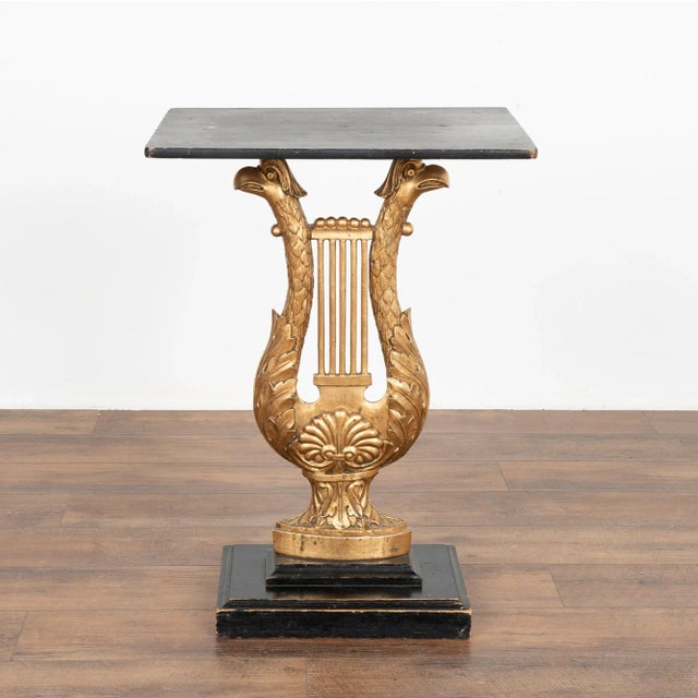 Dramatic eagle head carving in shape of harp form the base of this Neoclassical console table from Sweden. The gold...