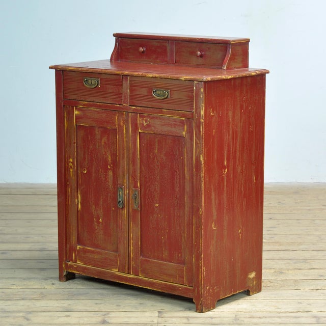 This pine cabinet from circa 1920 combines a timeless look with practical storage space. The piece features two small top...