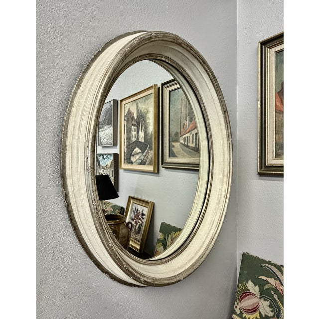 This French and Italian influenced oval wall mirror features a heavily molded, deep profile wood frame with distressed...