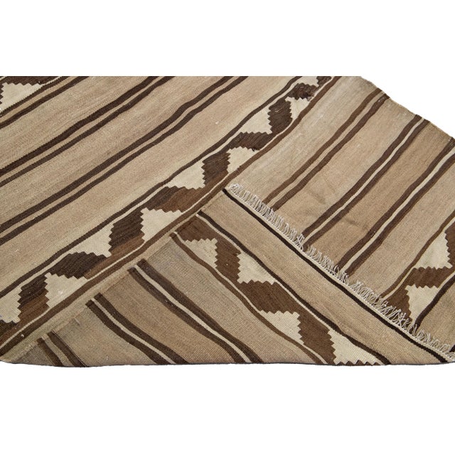 Beautiful kilim handmade wool runner with a brown field. This Vintage flatweave rug has beige and brown accents features a...