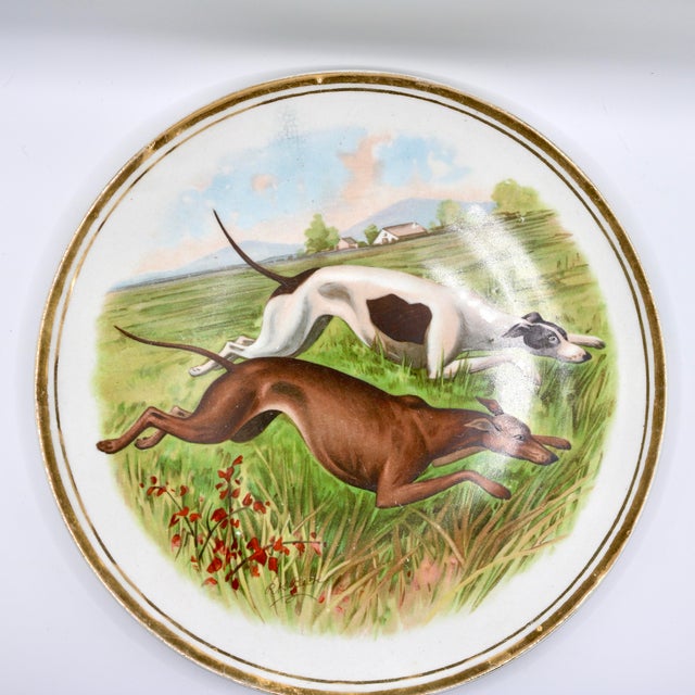 A beautiful antique porcelain cabinet plate featuring a dynamic sporting dog illustration by renowned wildlife artist R.K....