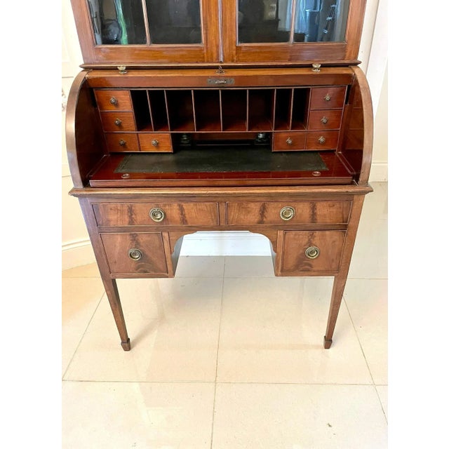 Antique Edwardian quality mahogany cylinder bookcase having a moulded shaped cornice, figured mahogany frieze above a pair...