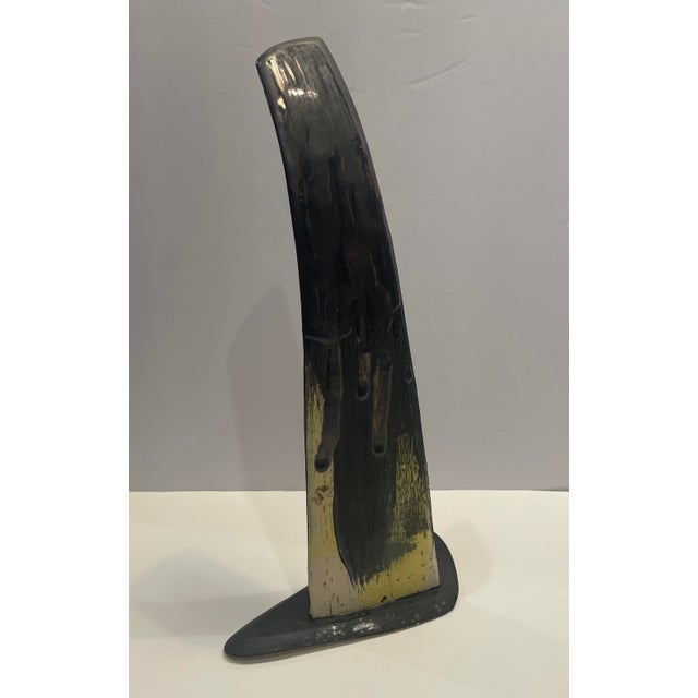 1990s glazed ceramic wing form sculpture, yellow and dripped black glaze with a triangular form base. Initialed J.I. on...