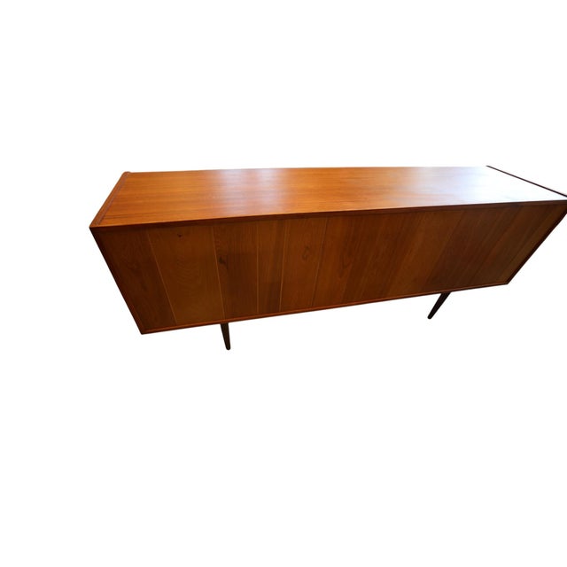An extremely elegant and tasteful sideboard in teak, designed by Johannes Andersen for Uldum Møbelfabrik in Denmark. An...