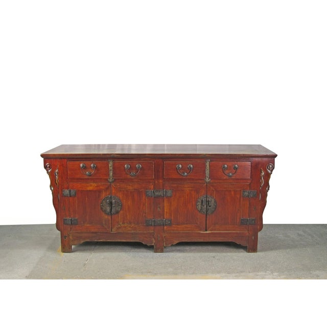 This deep rich reddish brown antique Chinese sideboard features handsome original brassware and hand carved boards on each...