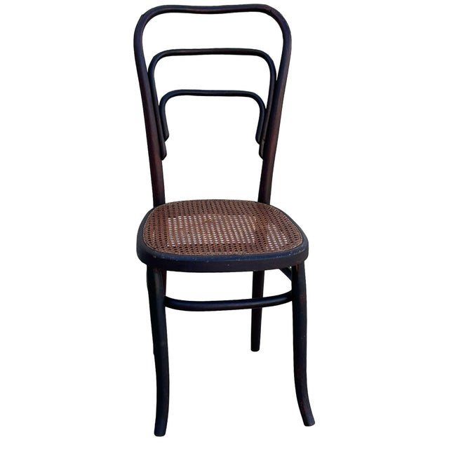 Early Modernist Thonet number 144 side chair features an elegant, sculptural frame crafted from warm-toned bentwood with...