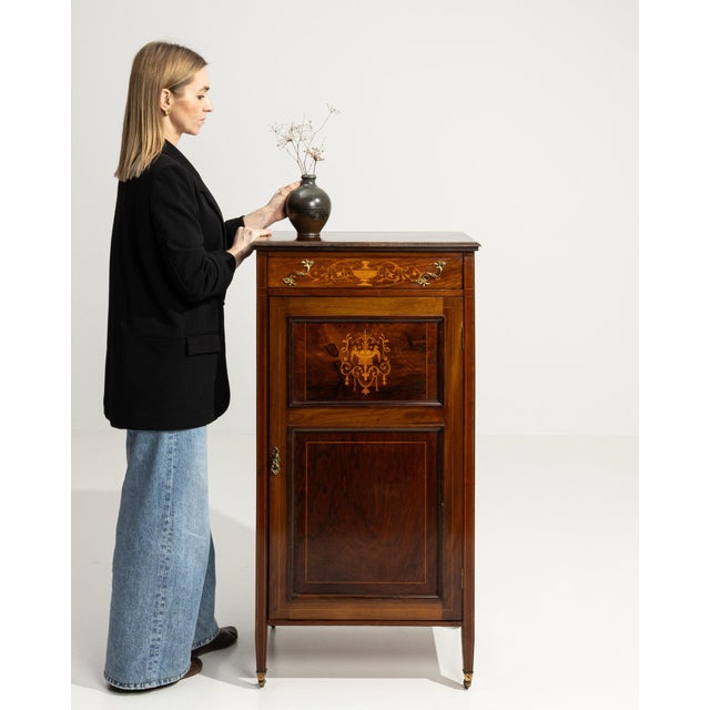 This piece presents as a side cabinet, distinguished by dark mahogany with inlay, drop-front, open showing shelf. The...