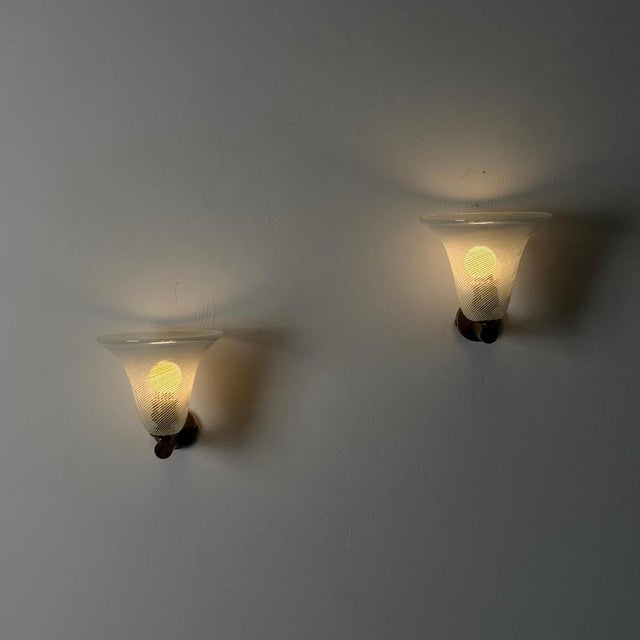 An elegant and highly sculptural pair of Venetian wall lights composed of finely worked torcello glass shades mounted on...