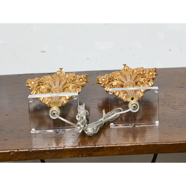 A pair of 19th century French giltwood fragments transformed into modern, sculptural table lamps, mounted on custom lucite...