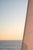 Minimalist coastal artwork featuring a sunlit sail against open water with soft golden tones and clean lines. The...