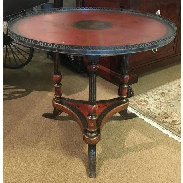 Unique tripod base table with lower shelf features painted wood frame with tooled leather accents painted with antique red...