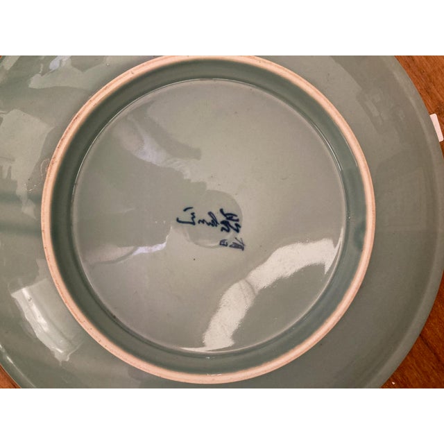 Celedon green background with illustrations of in navy blue of a crane and crane airborne flanked by pine trees, a bamboo...