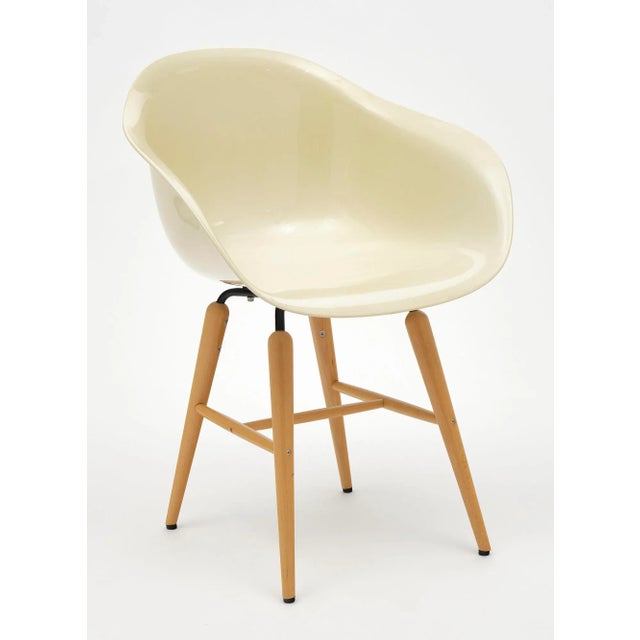 A pair of armchairs; one ivory; one white; made of molded plastic in the Eames style. They are supported by four natural...