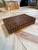 Rectangular wooden box featuring a sculptural grid of raised square details across the lid and sides. Warm amber and brown...