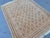 This hand-knotted Taimani rug showcases an allover diamond lattice in soft camel and ivory, accented with small rust-red...
