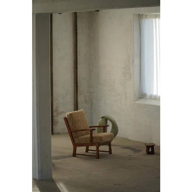 A stunning Danish Modern lounge chair in the style of Henning (Henry) Kjærnulf, crafted in solid oak with reupholstered...