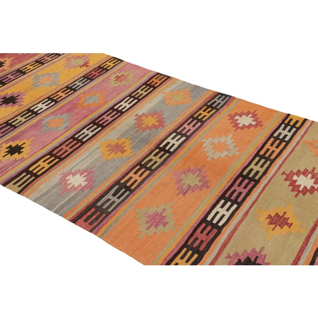 Originating from Turkey in 1960, this vintage Turkish wool kilim rug depicts an uncommon abundance of culturally...