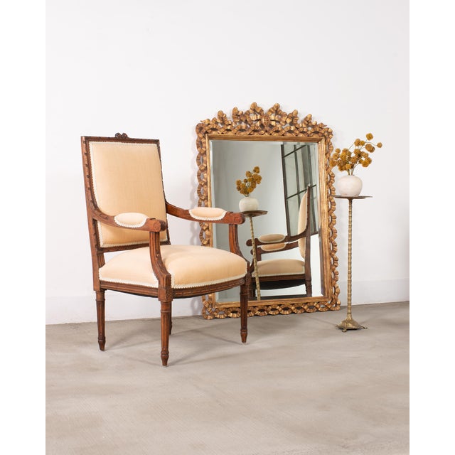 An opulent Italian Rococo-style giltwood wall mirror featuring a pierced, ribbon border. The ornate frame is constructed...