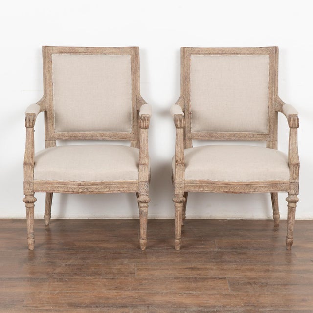 Pair, Swedish white painted armchairs with carved details along edges, top of back and bottom of seat; turned fluted legs....