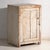 This antique cupboard in pine wood is a Central European rustic cabinet with a single door, a porcelain knob and worn...