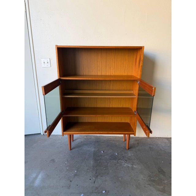 Elegant Mid Century Modern Danish display cabinet crafted in warm teak wood, dating to the 1960s and showcasing classic...