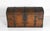 A commanding dome-top coffer in oak, bound front and lid with hand-wrought iron strapwork in scrolling foliate forms. The...