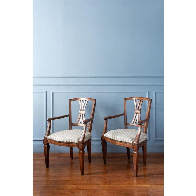 A pair of early 19th-century French provincial walnut armchairs, each with distinctive tapered legs and gracefully...