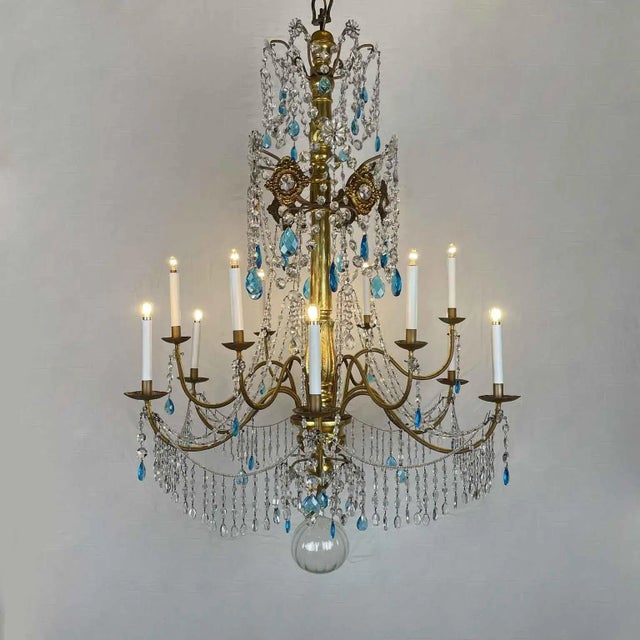A Genoese twelve-light gilded Empire chandelier, composed of a turned, carved, and gilded wooden shaft and twelve gilded...