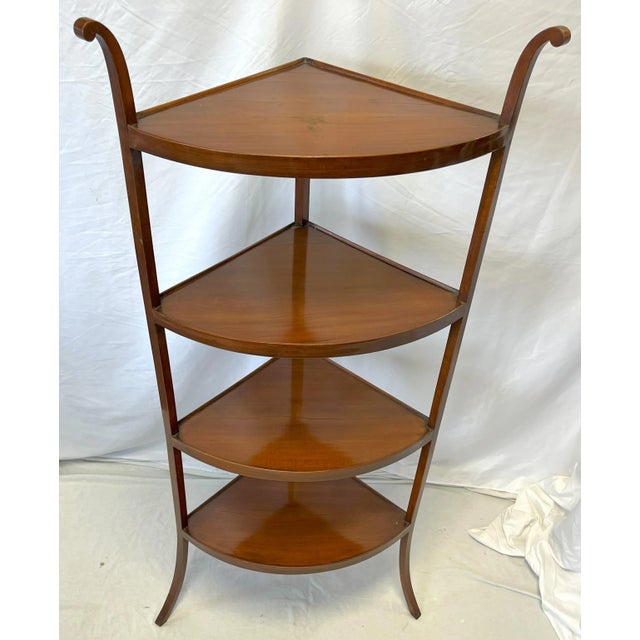 A timeless mid century modern corner shelf unit. It is made of wood with a cherry veneer finish, and has four shelves...