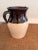 Charming vintage two-tone stoneware pitcher featuring a rich chocolate brown glazed upper body over warm cream pottery...
