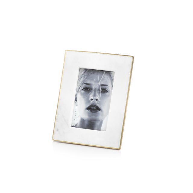 White marble frame features matt gold brass edge and holds 4 inches x 6 inches photo inserted through back of frame....
