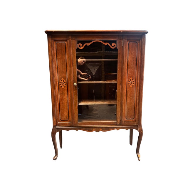 An elegant antique Queen Anne style display cabinet crafted in warm walnut, dating to circa 1920s. With its graceful...