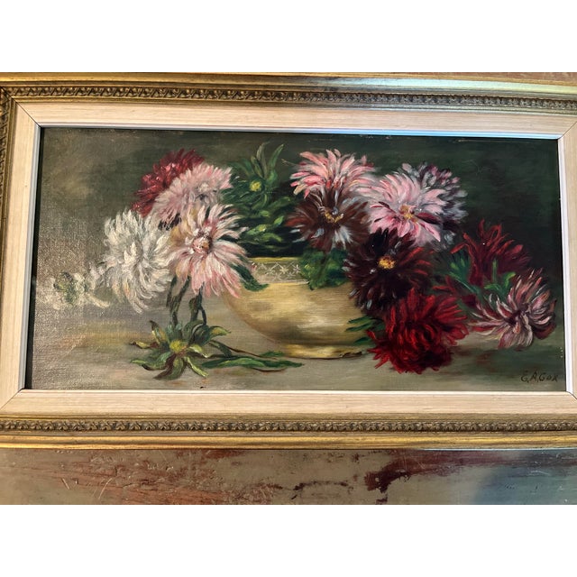 The composition features a lush arrangement of chrysanthemums and dahlia-like blossoms overflowing from a classical...