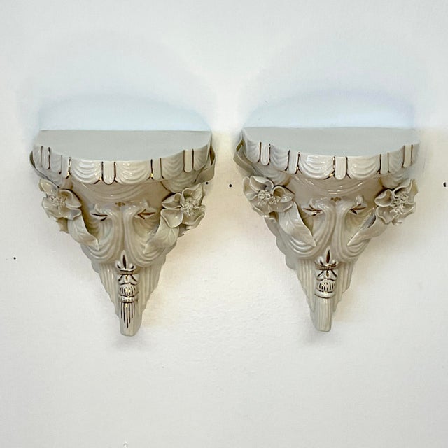 These are a pair of porcelain wall brackets by the American company Lee Wollard. They feature a draped faux fabric swag...
