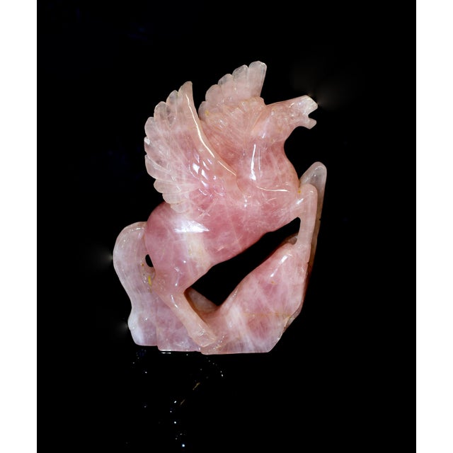 A striking hand-carved sculpture of Pegasus, the mythical winged horse, exquisitely rendered in natural rose quartz....