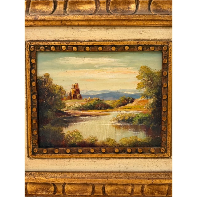 A charming vintage landscape painting depicting a serene riverside scene with rolling hills, lush greenery, and a distant...
