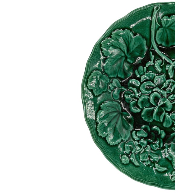 English majolica green-glazed 9.13-inch plate, with relief molded geranium plants and blossoms, with a shaped rim; the...