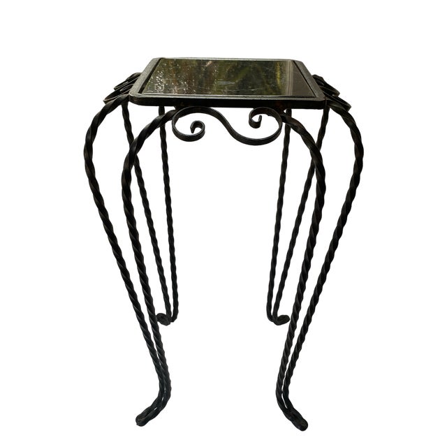 Black, wrought iron, hand made table with twisted iron legs, ornate scrollwork and a black ceramic insert surface. An...