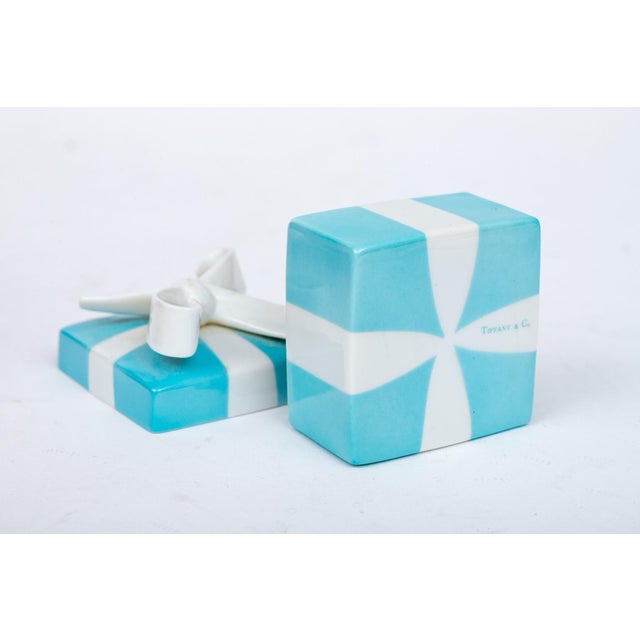 An authentic Tiffany & Co. porcelain trinket box shaped like the brand's iconic blue gift box. Features a square base with...