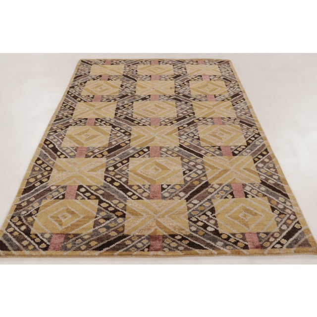 This 6x9 contemporary Scandinavian rug showcases a repeating geometric pattern in ochre, brown, mauve, and gray tones....