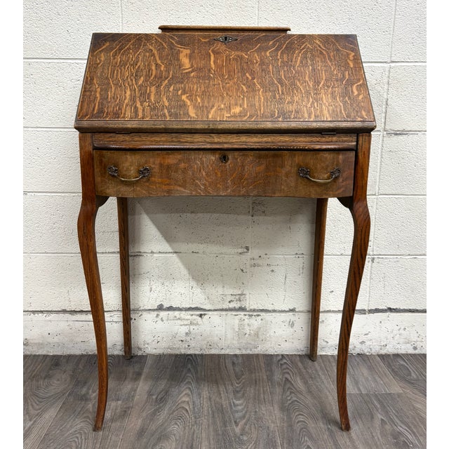 Charming antique oak slant-front secretary desk featuring a graceful silhouette, beautiful oak grain, and elegant Queen...